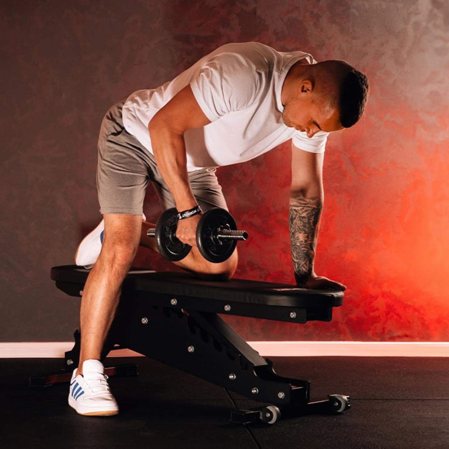 Man performing bench press on flat adjustable bench